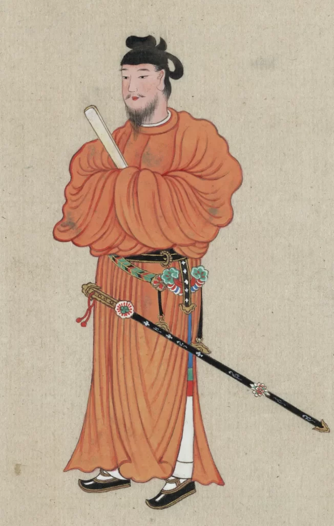 This image contains a painting of Prince Shotoku, a very important political figure during the Asuka period of Japan in the 7th century. He is depicted wearing a flowing orange robe with his arms followed in front of one another, holding what appears to be a fan in his left hand. He is wearing his hair up in a bun. At his waist lies an ornate belt from which a ceremonial sword is held. There is a slit running up the sides of his robe revealing his legs and multicolored pants underneath.