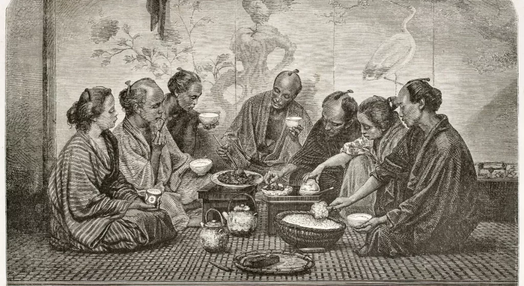 This is a painting of a Japanese family during a meal. They are all pictured sitting around the various food items. Some members are pictured holding bowls, with one even taking a sip. The man in the middle of the frame is seen doleing out food to another member.
